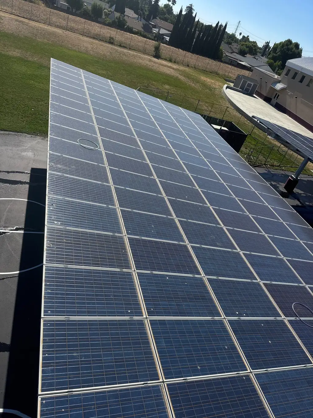 Clean school district solar carport panels overlooking an athletic field, Pittsburg CA